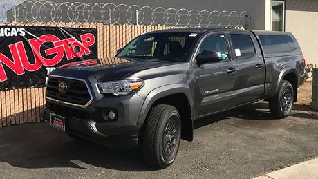 A toyota tacoma truck is parked in front of a building.