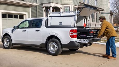 A man is loading something into the back of a white truck.