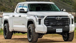A white toyota tundra is parked on a dirt road.