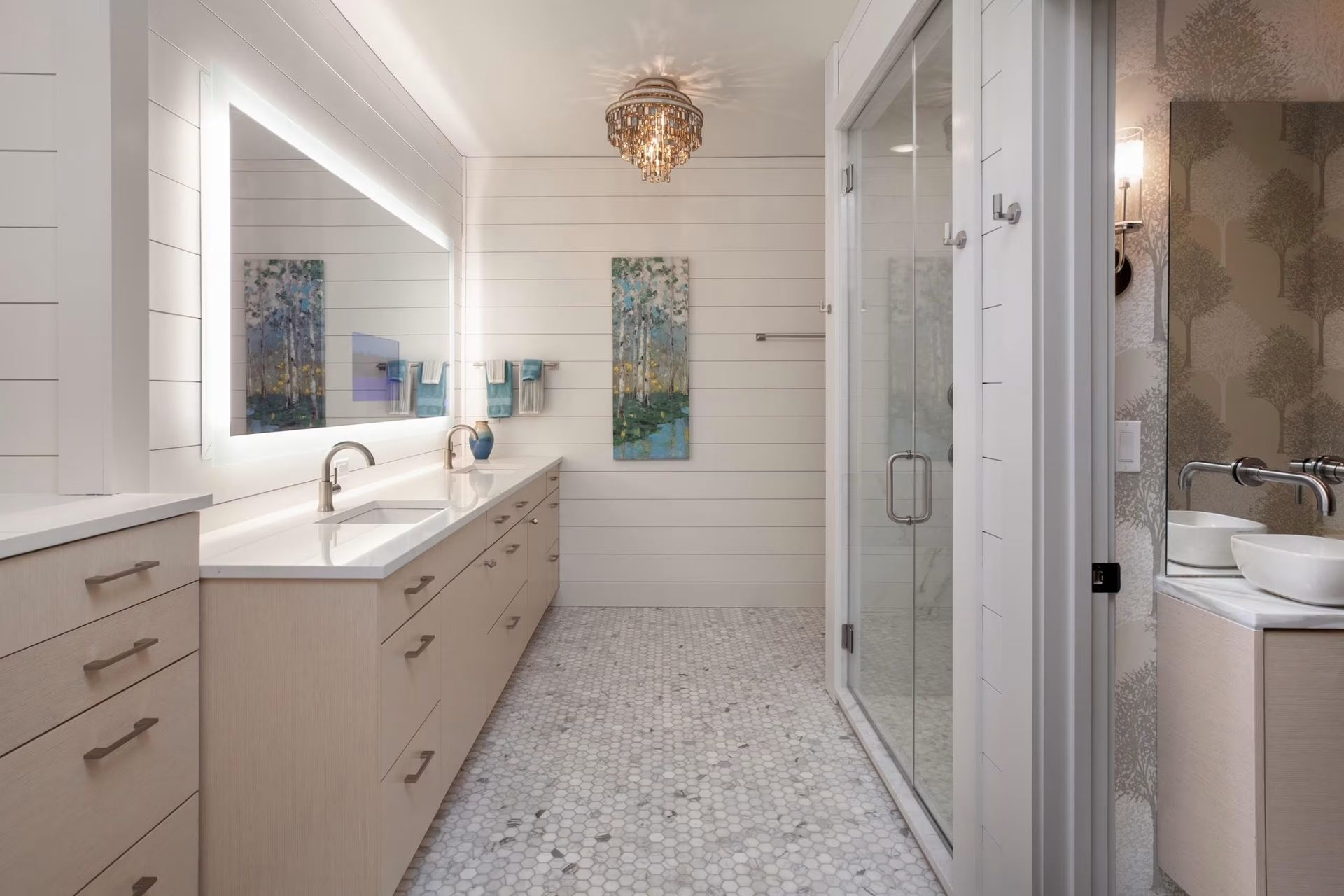 Bright modern bathroom with double vanity, large mirror, glass shower, and white tile floor.