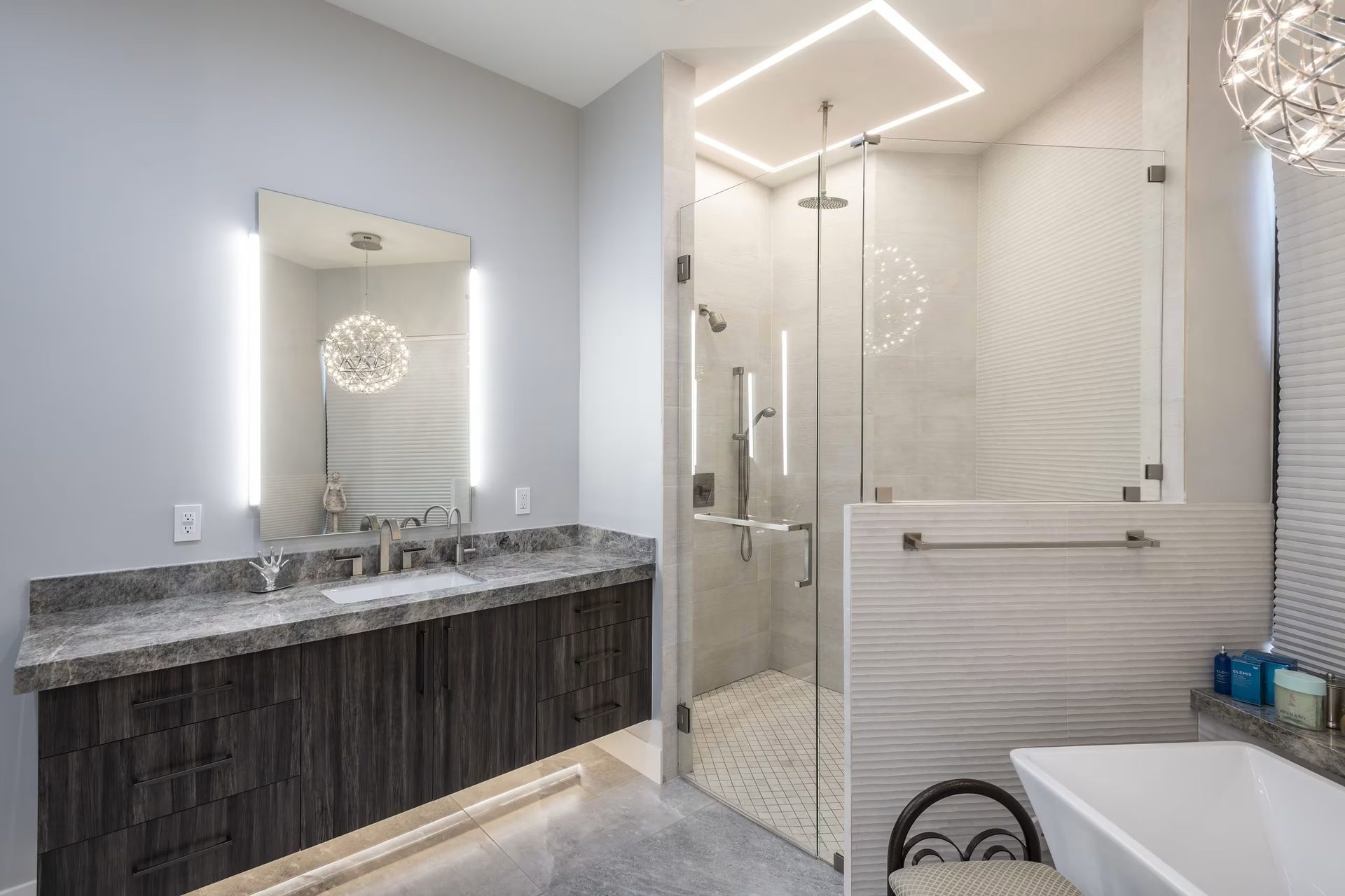 Modern bathroom with double vanity, backlit mirror, and glass-enclosed shower