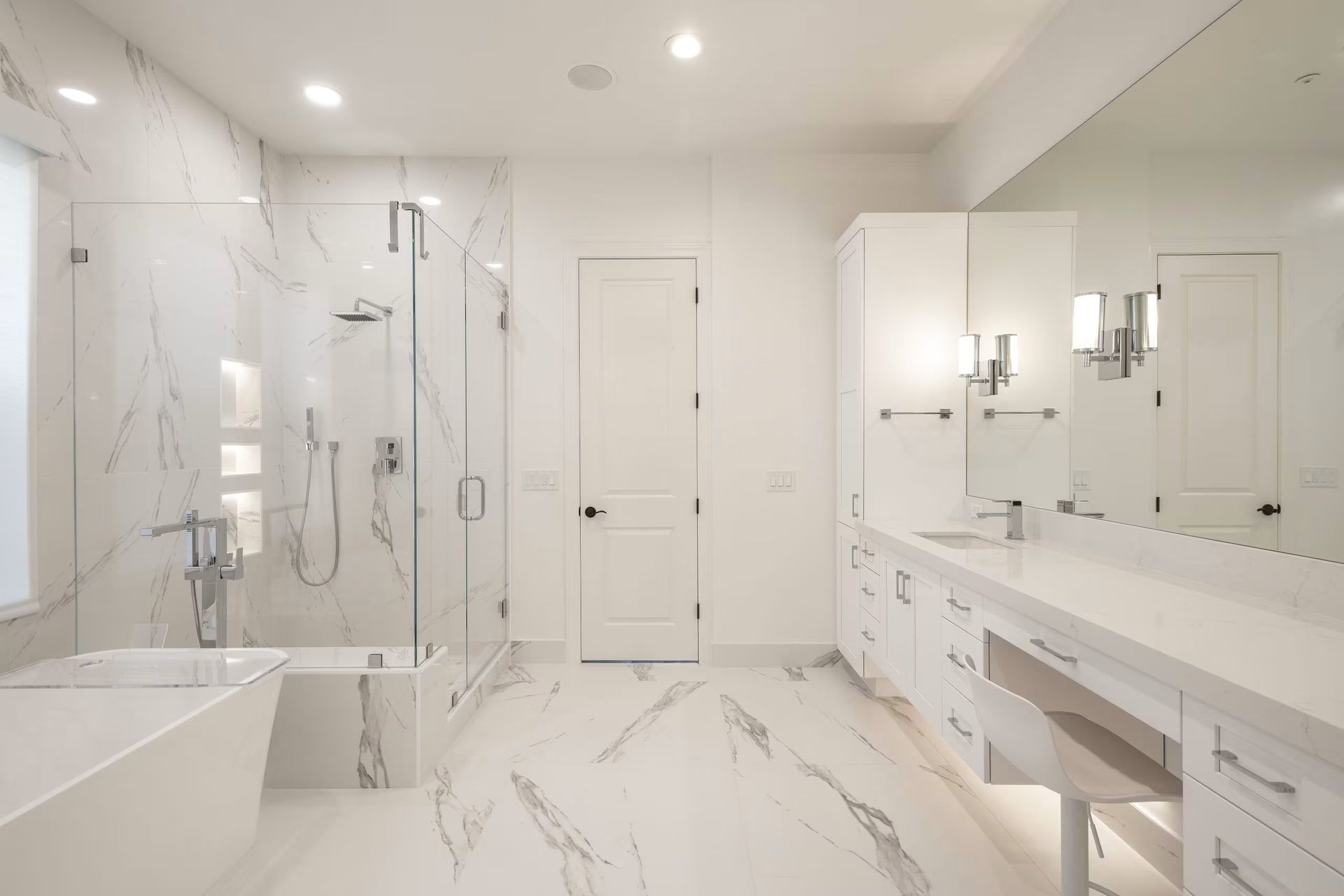 Bright white modern bathroom with marble tile, glass shower, double vanity, and freestanding tub