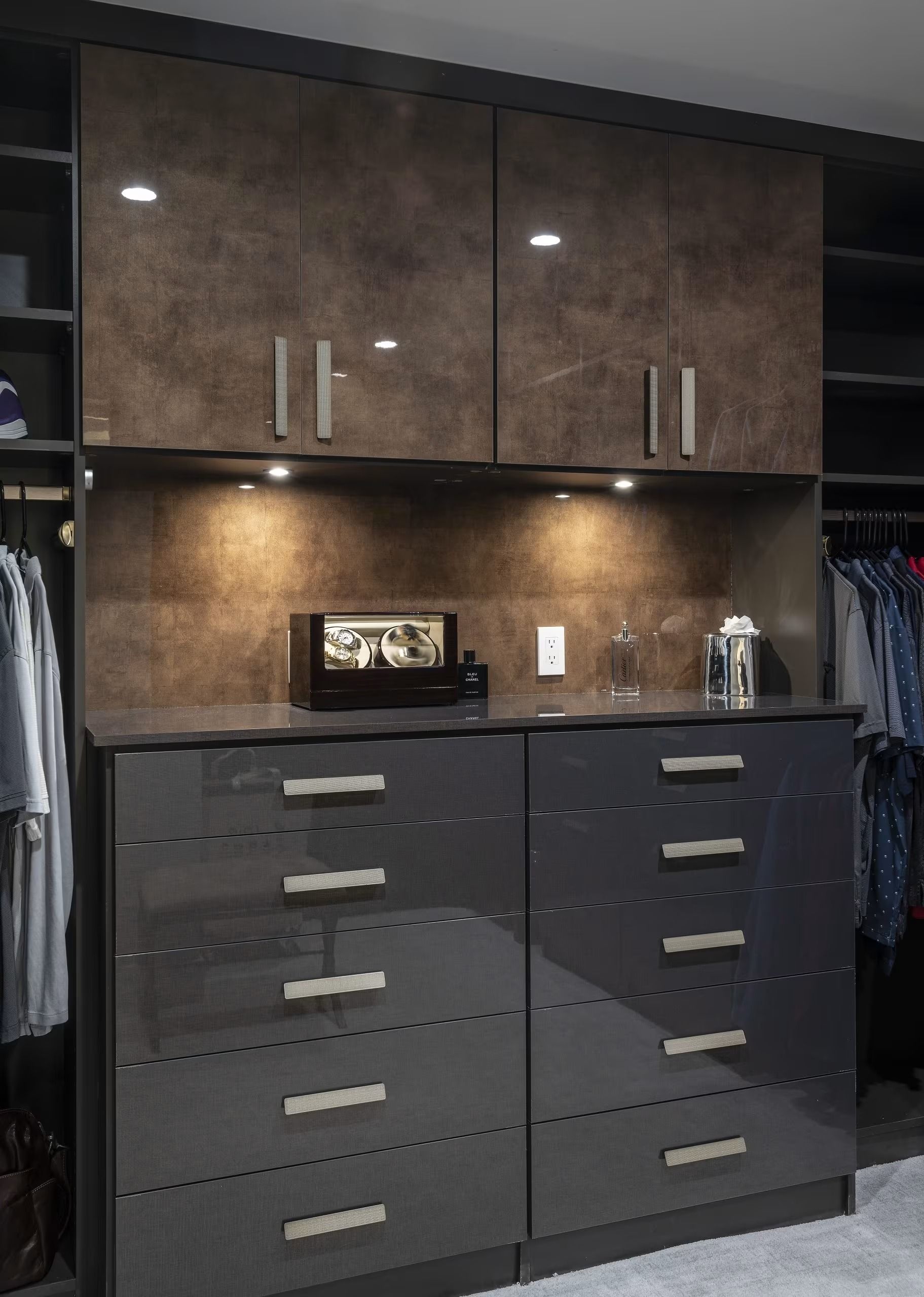Built-in dark wood cabinets and black drawers with under-cabinet lighting in a closet or dressing room