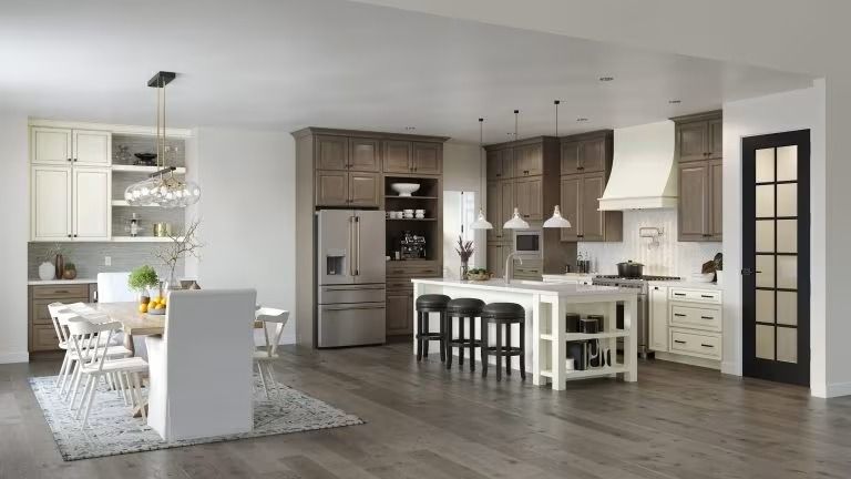 Bright modern kitchen and dining room with white cabinets, gray island, and wood flooring