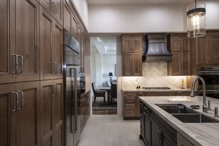 Modern kitchen with dark wood cabinets, stainless appliances, and a central island with sink