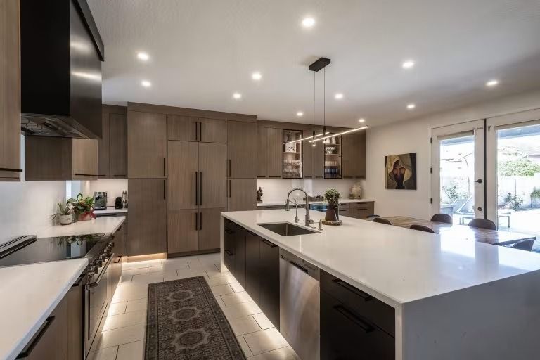 Modern kitchen with large island, white countertops, dark cabinetry, and recessed ceiling lights
