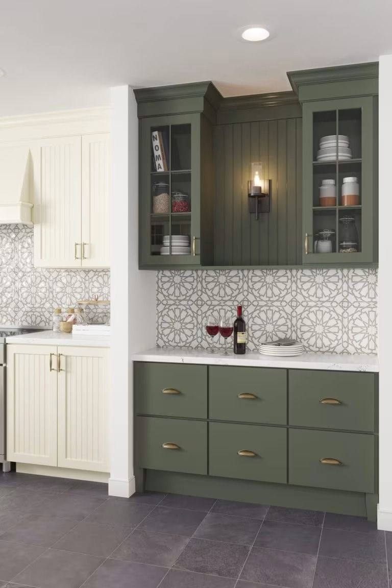 Green built-in kitchen cabinets with glass doors, white countertop, and patterned backsplash in a modern kitchen nook