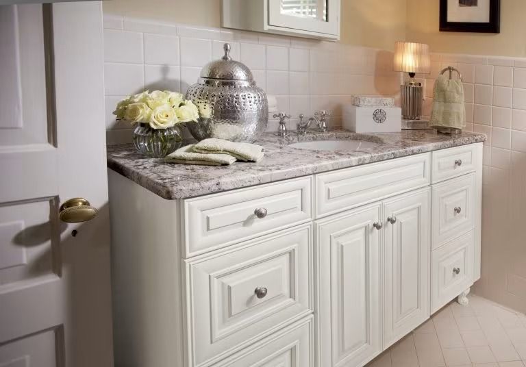 Elegant white kitchen vanity with marble countertop, flowers, and silver tea set