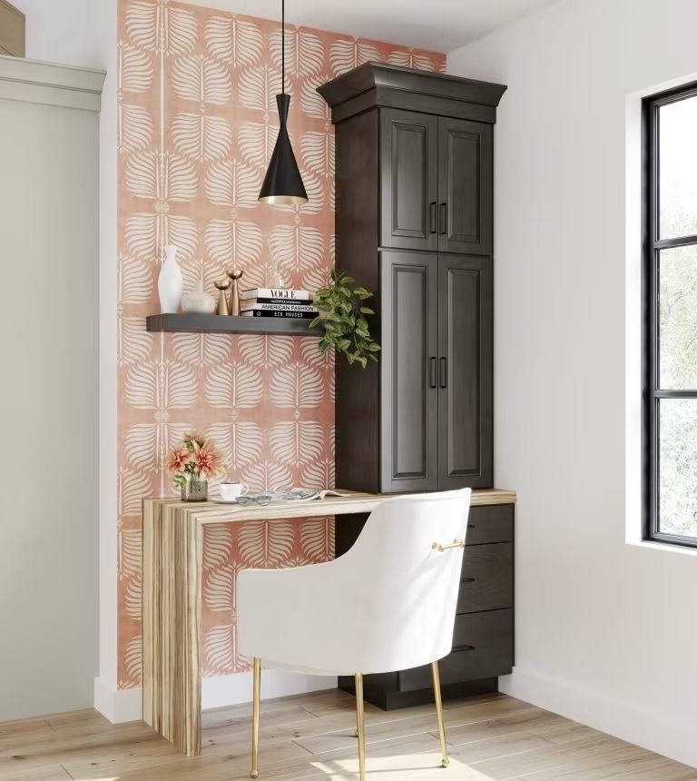 Stylish home office with desk, white chair, tall dark cabinet, and peach patterned accent wall