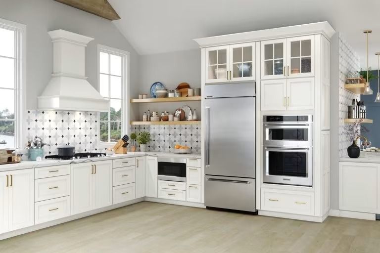 Bright white modern kitchen with stainless steel appliances, tiled backsplash, and light wood floor