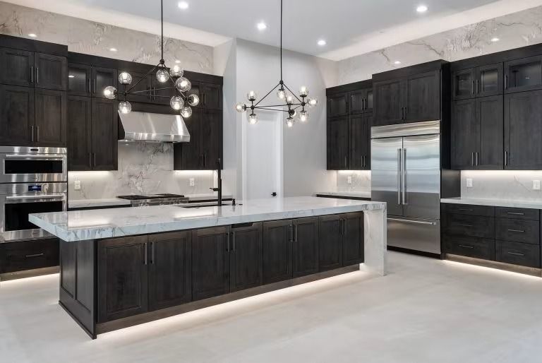 Modern black-and-white kitchen with large island, stainless steel appliances, and pendant lighting