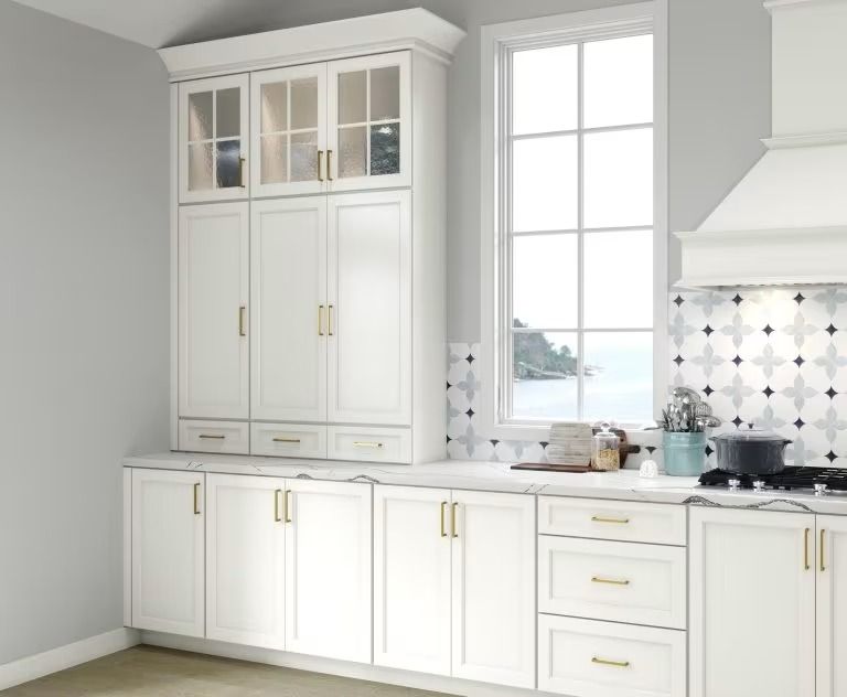 Bright white kitchen with tall cabinets, a large window, and a black-and-white tiled backsplash
