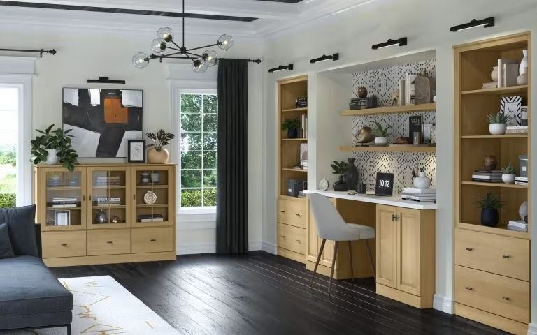 Modern living room with dark sofa, wood cabinets, desk, shelving, and large windows with black curtains.