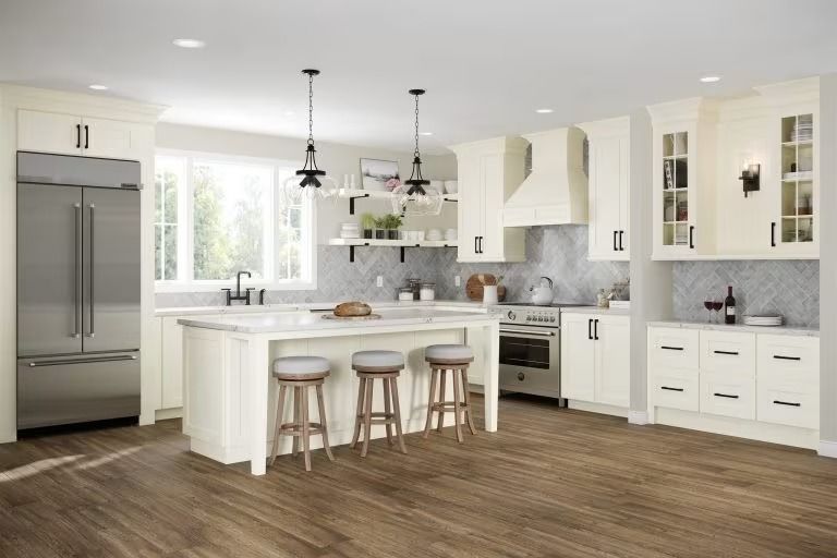 Bright white modern kitchen with island, bar stools, stainless fridge, and wood flooring.