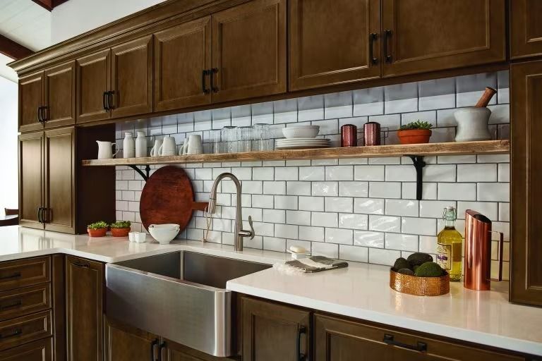 Modern kitchen with dark wood cabinets, white subway tile, stainless sink, open shelves, and potted herbs