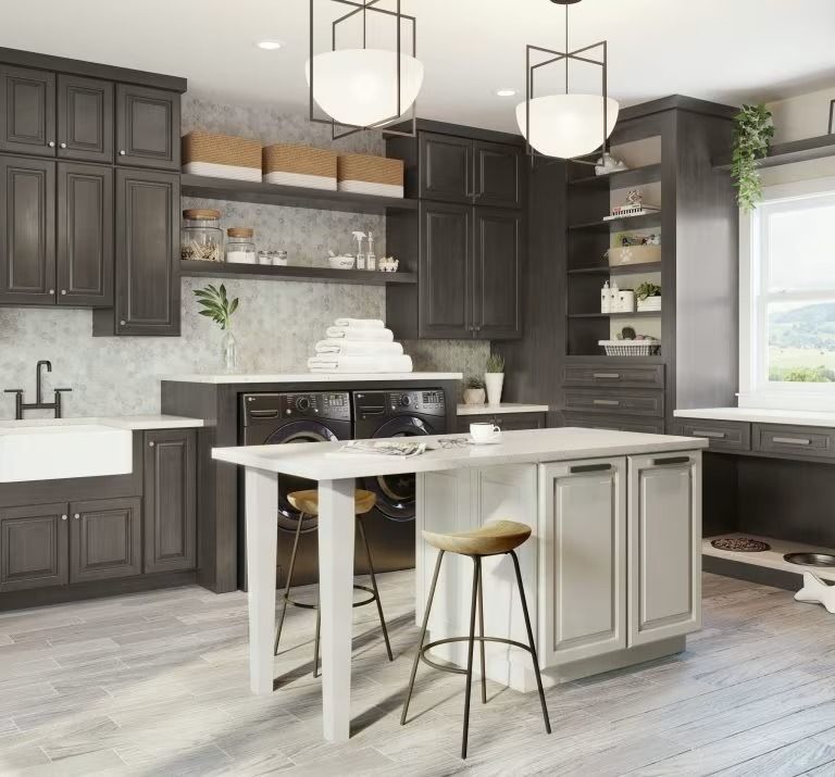 Modern kitchen with dark cabinets, white island, pendant lights, and light wood flooring