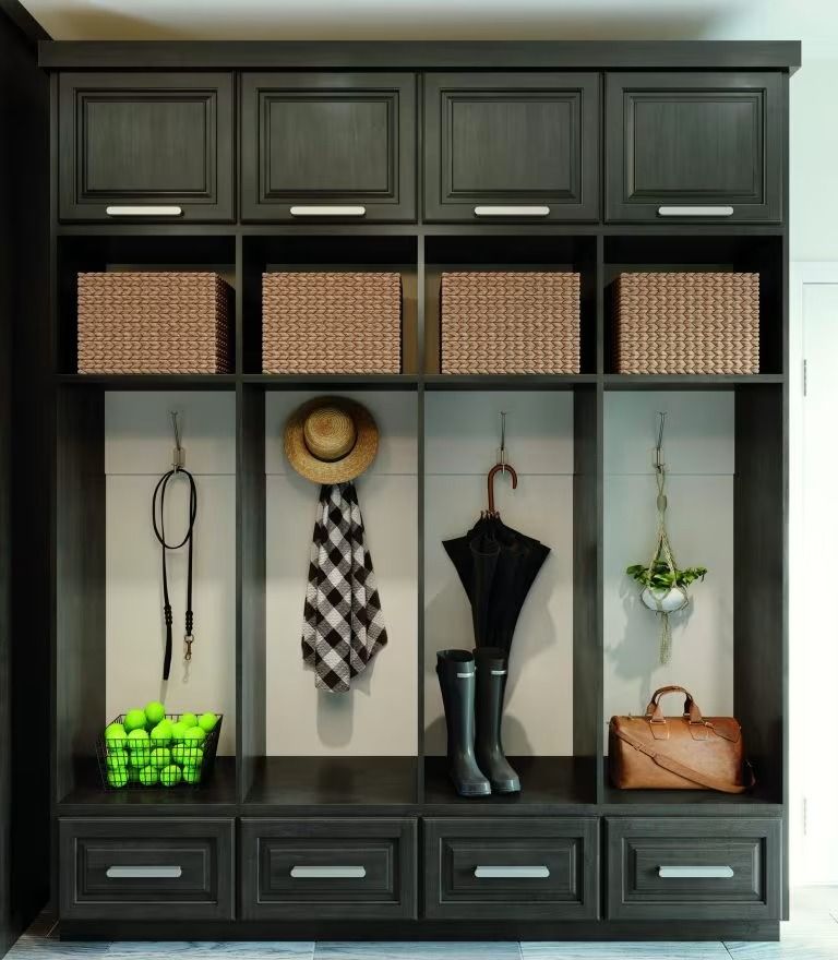 Dark wood entryway cabinet with woven baskets, hats, scarves, boots, and handbags arranged in cubbies