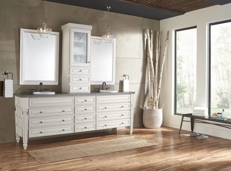 Bright bathroom with white double vanity, large mirrors, and wood floors by tall windows