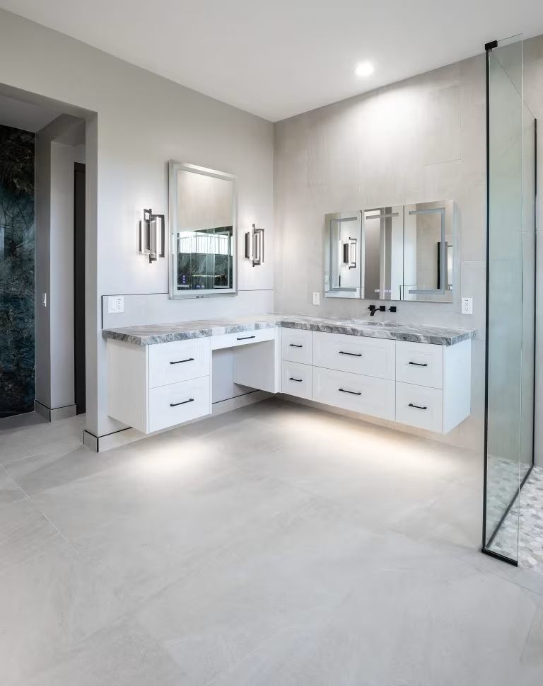 Modern white bathroom vanity with dual sinks, large mirrors, and glass shower enclosure