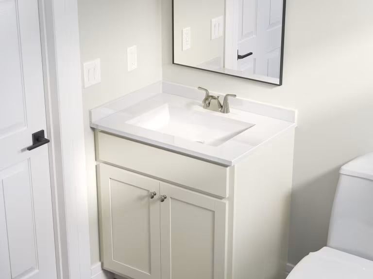 Small white bathroom vanity with sink, mirror, and light-colored walls.