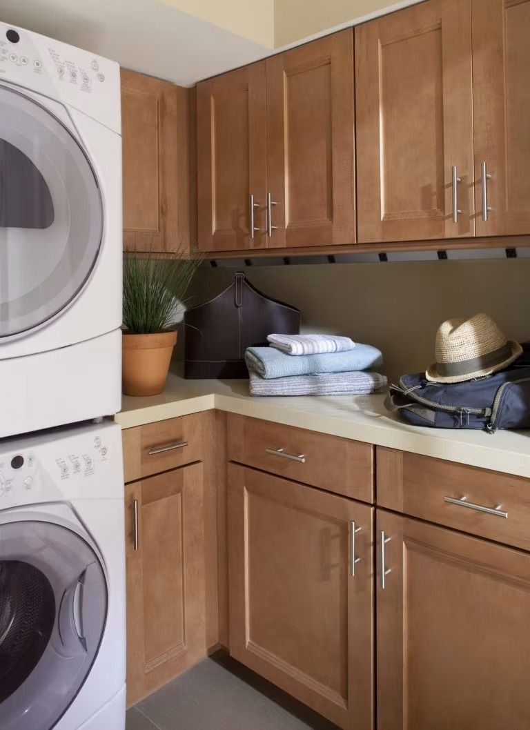 Laundry room with stacked washer and dryer, wood cabinets, countertop, and folded towels
