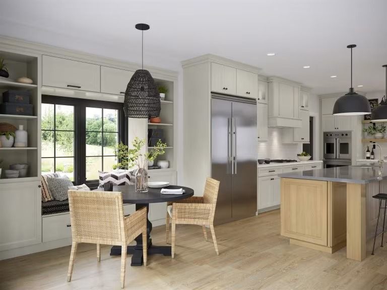 Bright modern kitchen with island, dining table, large windows, and wicker chairs