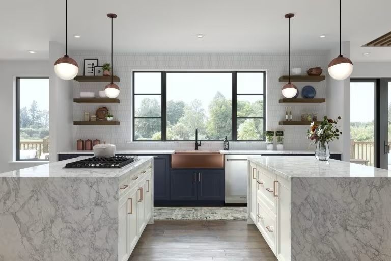 Bright modern kitchen with marble islands, dark cabinets, pendant lights, and large windows