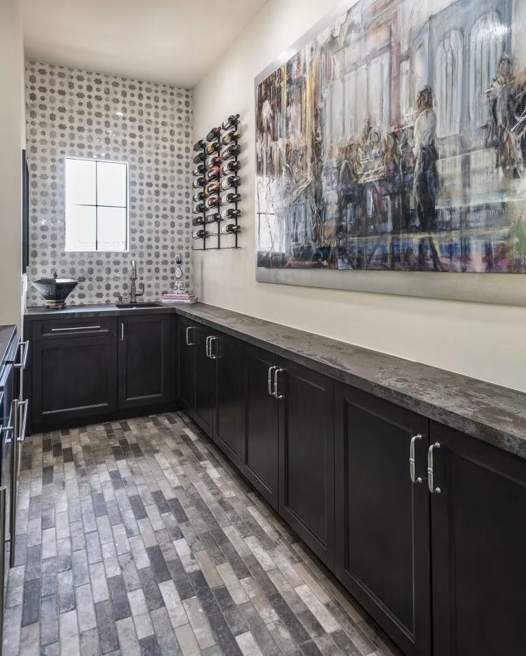 Modern bathroom with dark cabinets, gray tile floor, mosaic wall, and abstract wall art