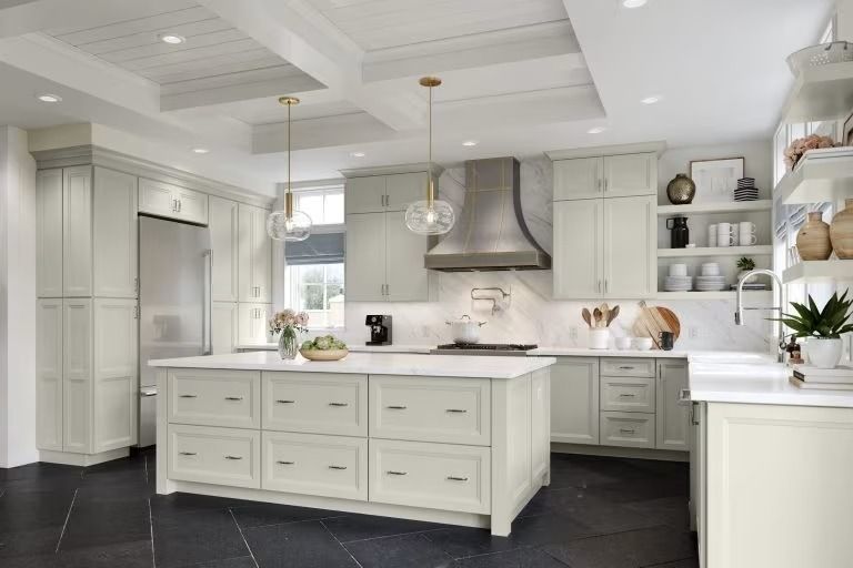 Bright white modern kitchen with large island, gray cabinets, and stainless range hood