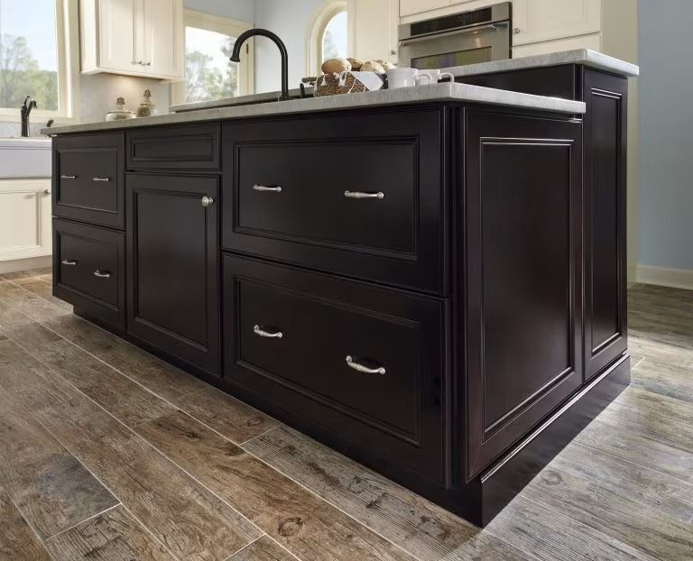 Dark kitchen island with black cabinetry and a white countertop on a tiled floor