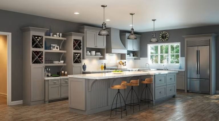 Modern gray kitchen with island, pendant lights, bar stools, and stainless steel refrigerator