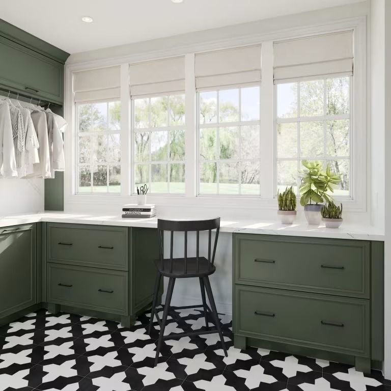 Bright home office with green built-in desk, black chair, large windows, and patterned black-and-white rug