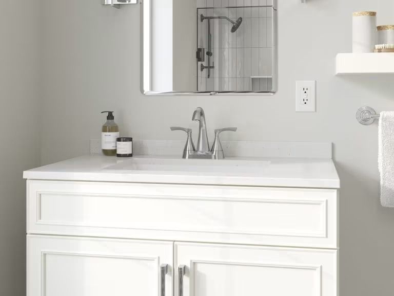 White bathroom vanity with sink, mirror, faucet, and wall shelf in a bright, minimalist space