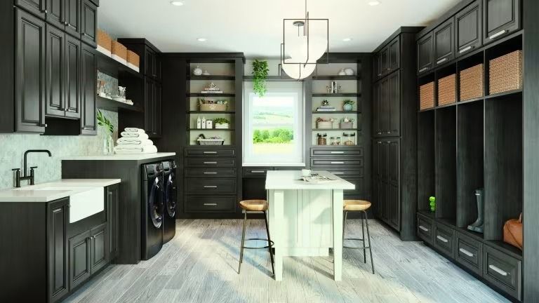 Modern black-and-white kitchen with island, cabinets, washer, and pendant light centered over a dining table.