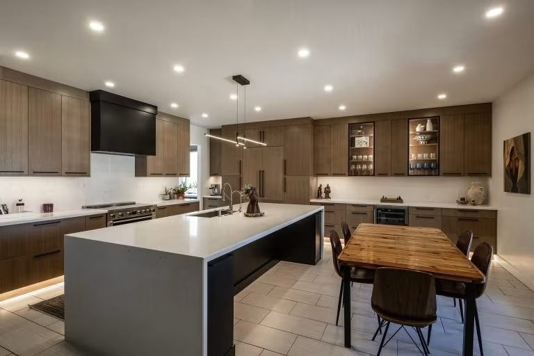 Modern kitchen with a large island, wood cabinets, tiled floor, and a dining table with chairs