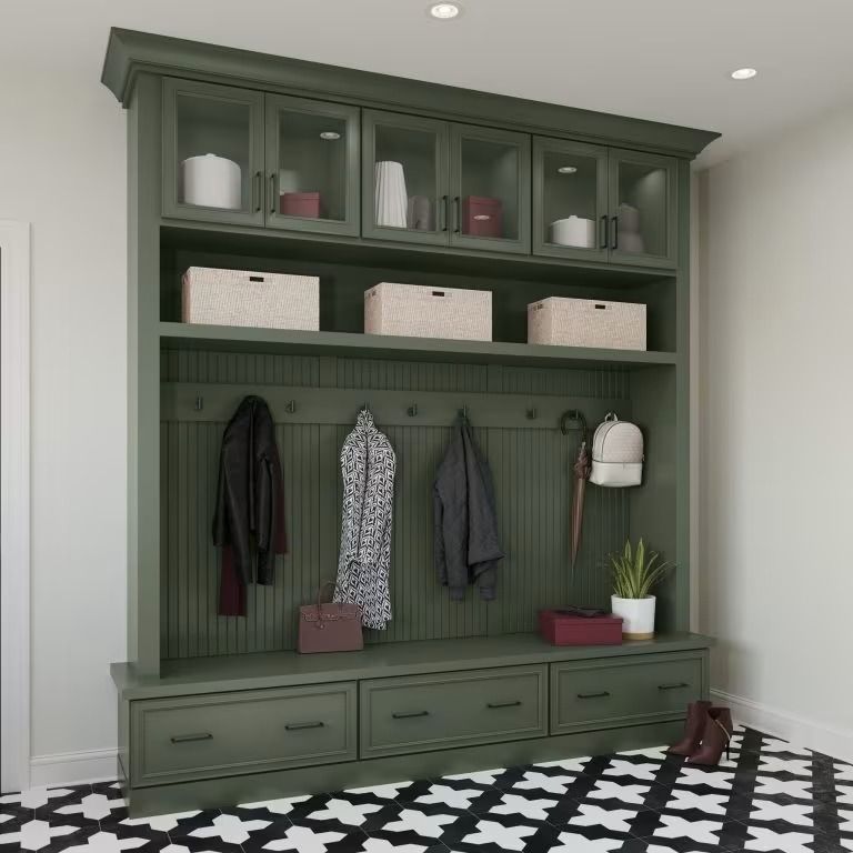 Green built-in mudroom bench with hooks, shelves, baskets, and coats in a tiled entryway.