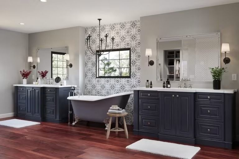 Modern bathroom with double vanity, freestanding tub, dark cabinets, and patterned accent wall