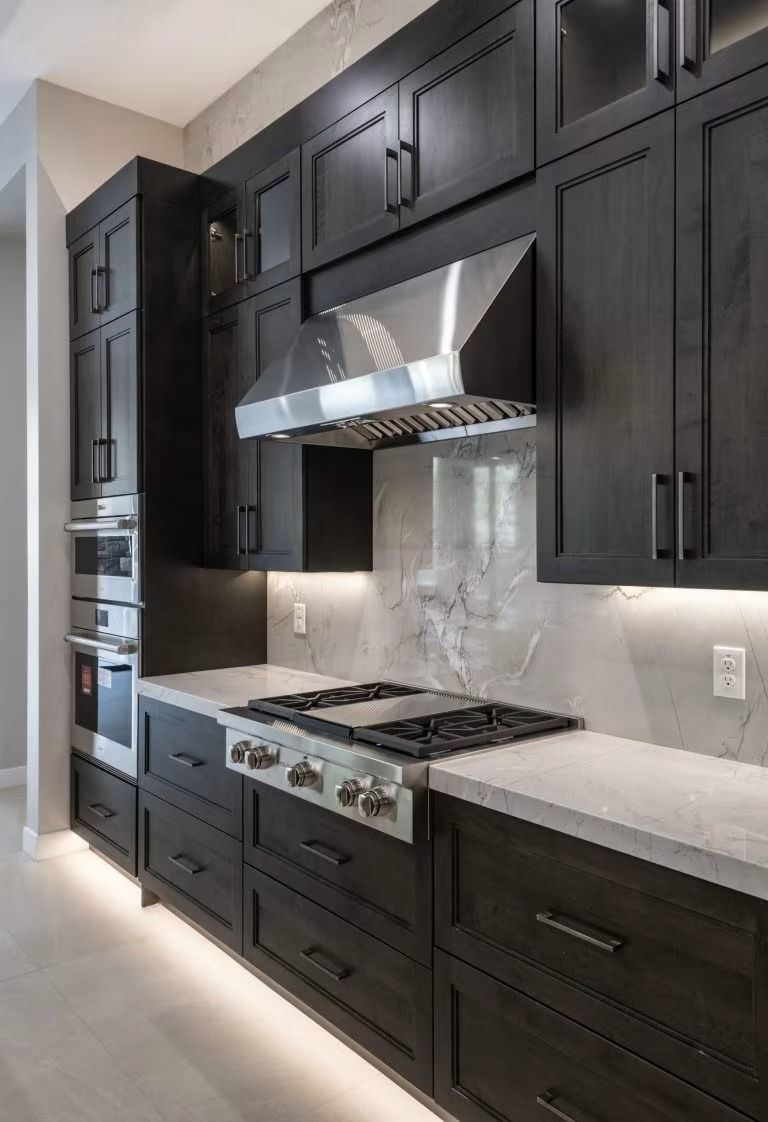Modern kitchen with dark wood cabinets, marble backsplash, stainless steel range hood, and gas cooktop