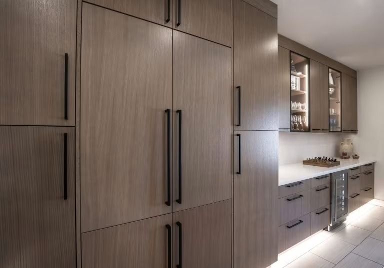 Modern kitchen with wood cabinets, black handles, and a white countertop under warm lighting