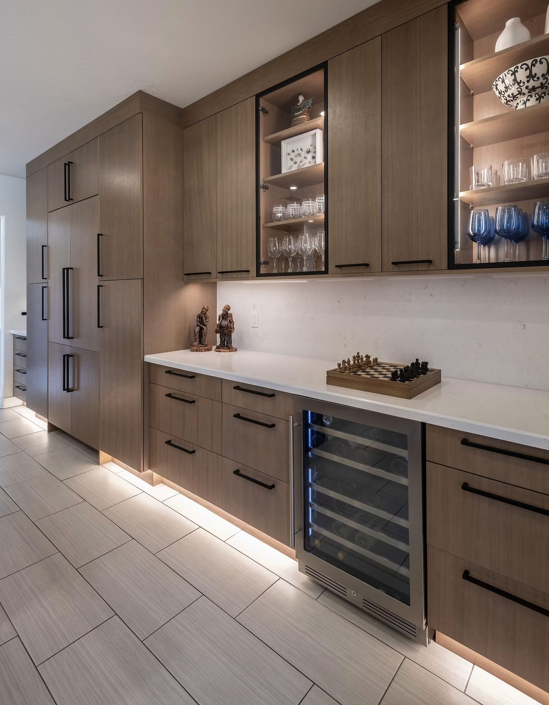 Modern kitchen with wood cabinets, white countertops, built-in wine fridge, and under-cabinet lighting