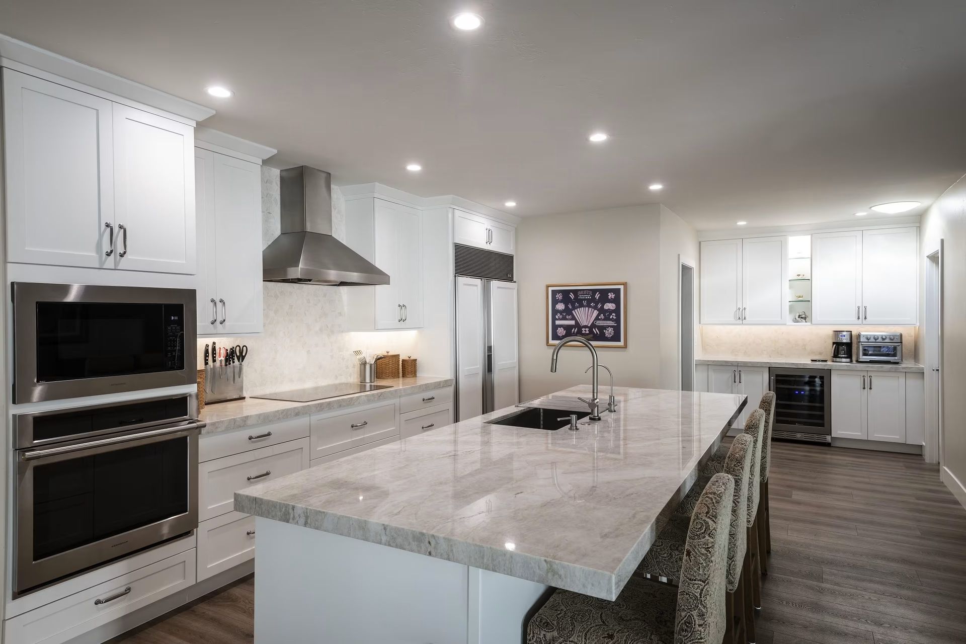 Bright modern kitchen with white cabinets, large marble island, and stainless steel appliances