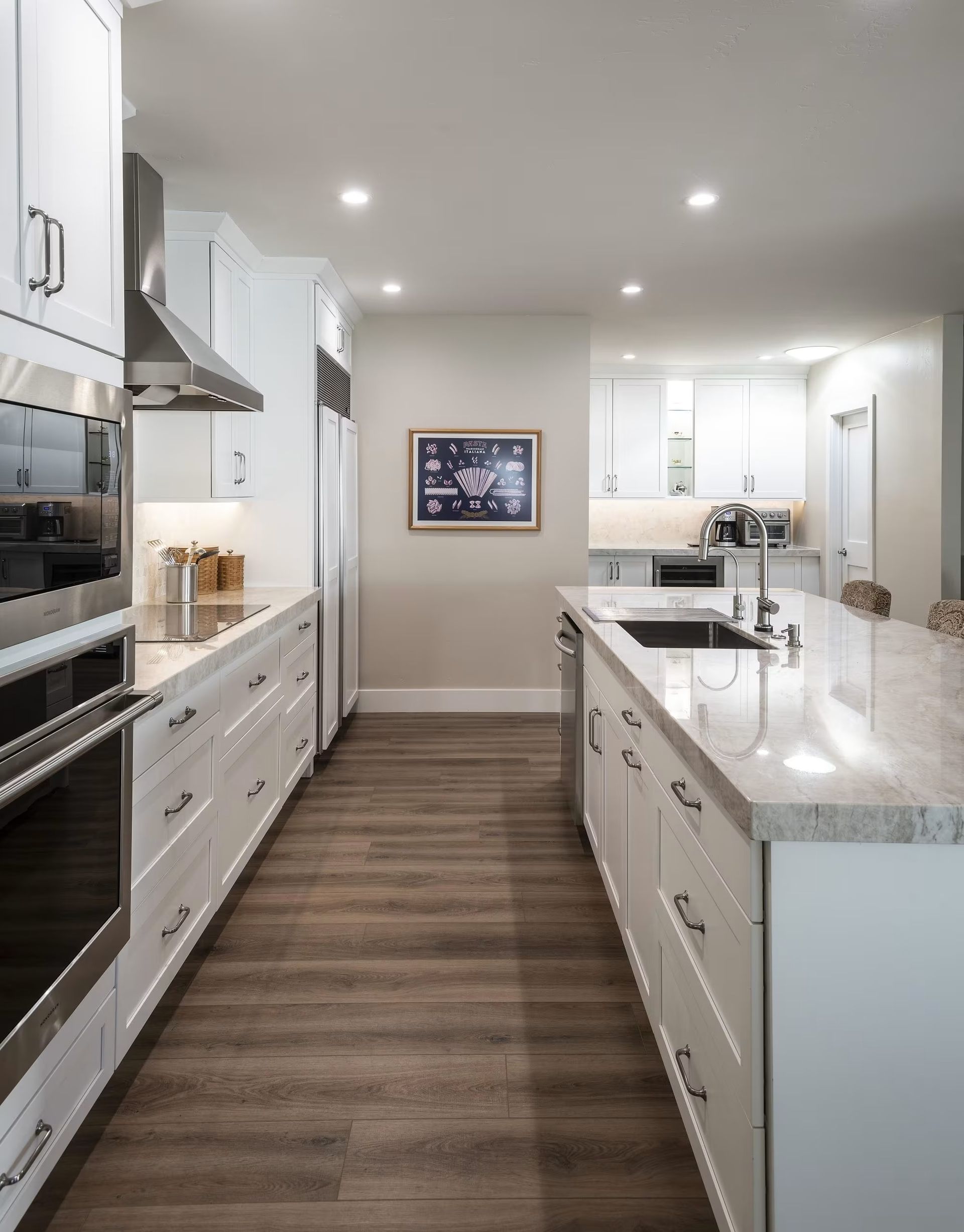 Bright modern kitchen with white cabinets, marble island, and wood flooring
