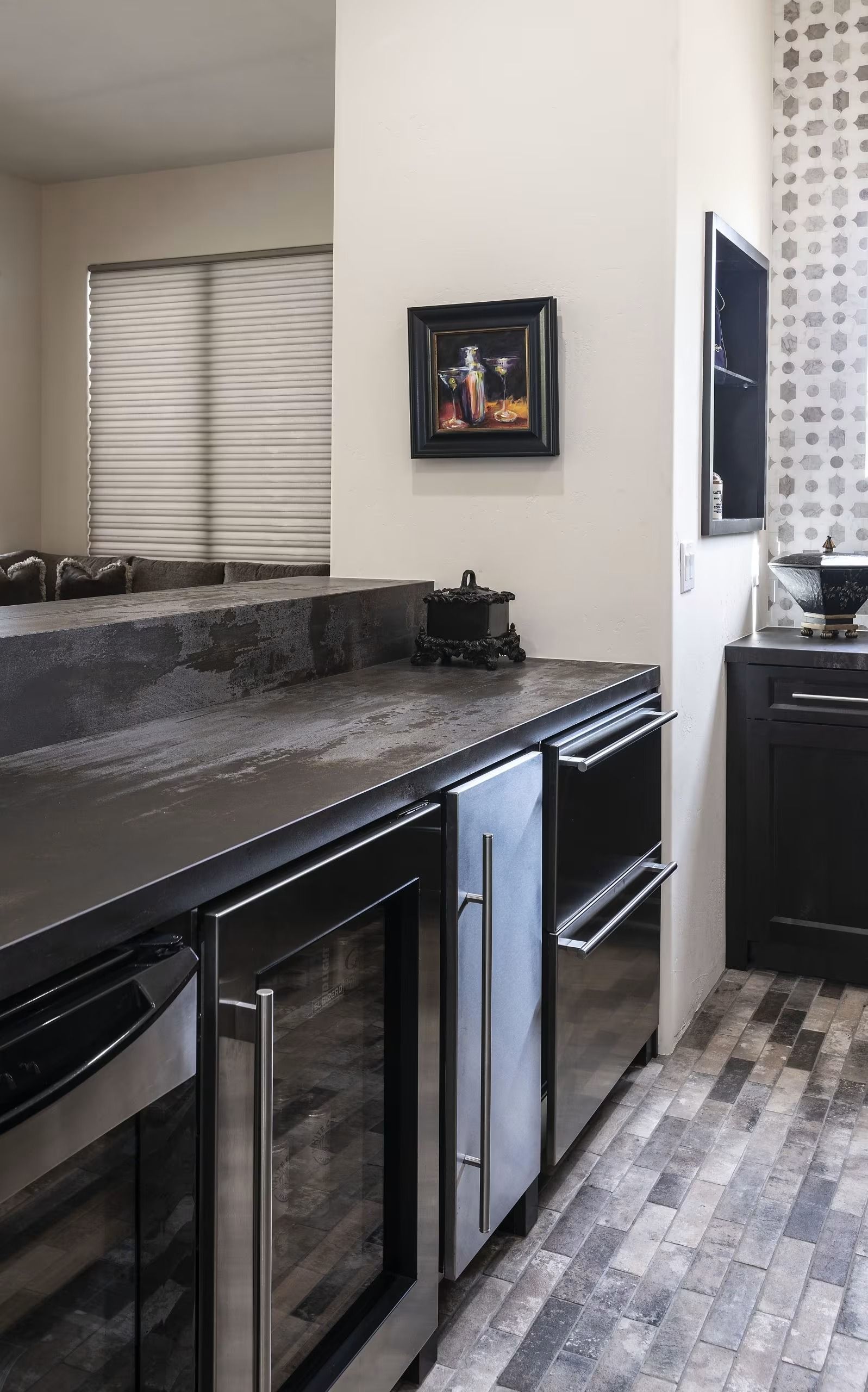 Modern kitchen with dark countertops, black mini-fridge, tile floor, and a small wall frame.