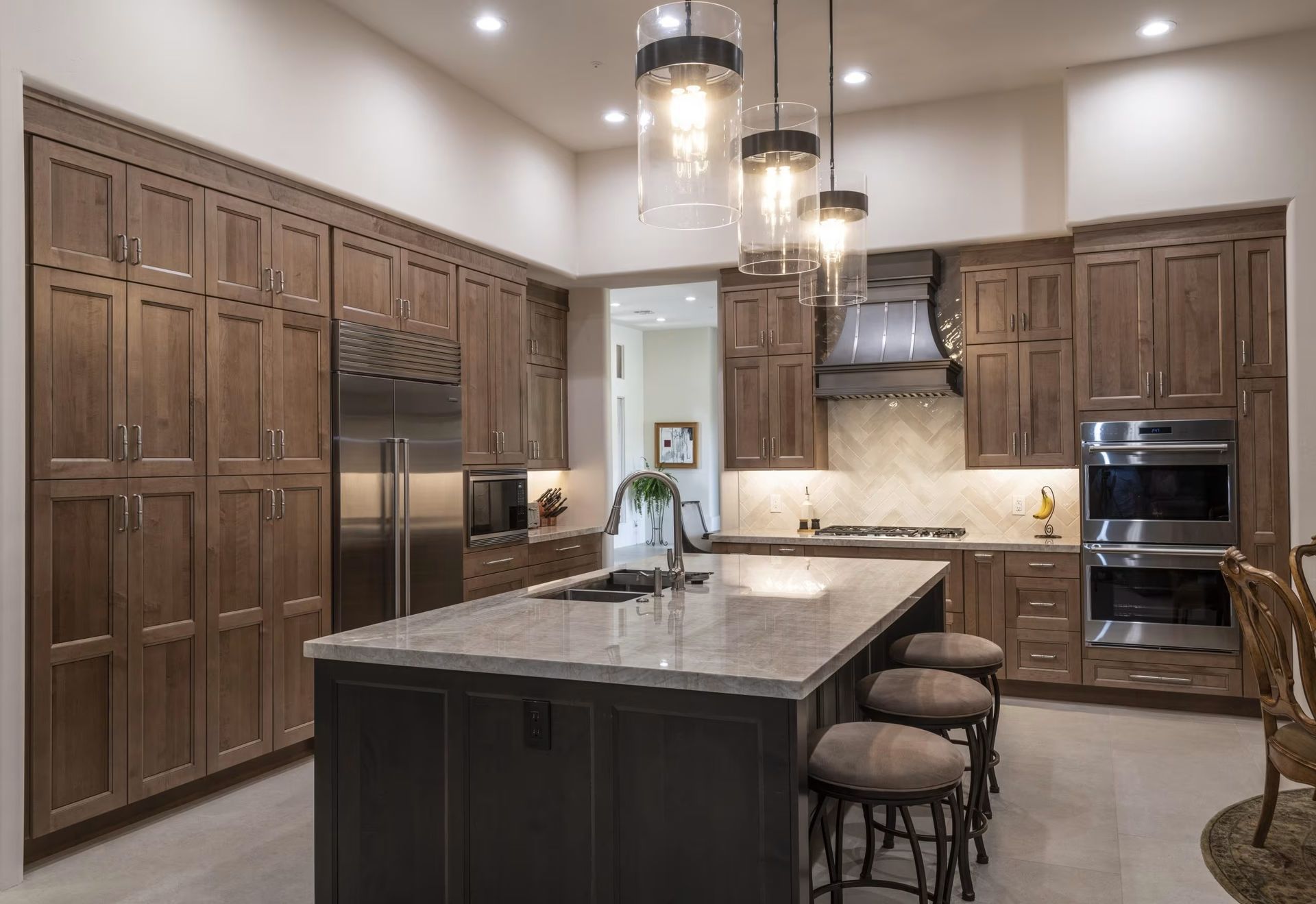 Modern kitchen with dark wood cabinets, large island, pendant lights, and built-in appliances