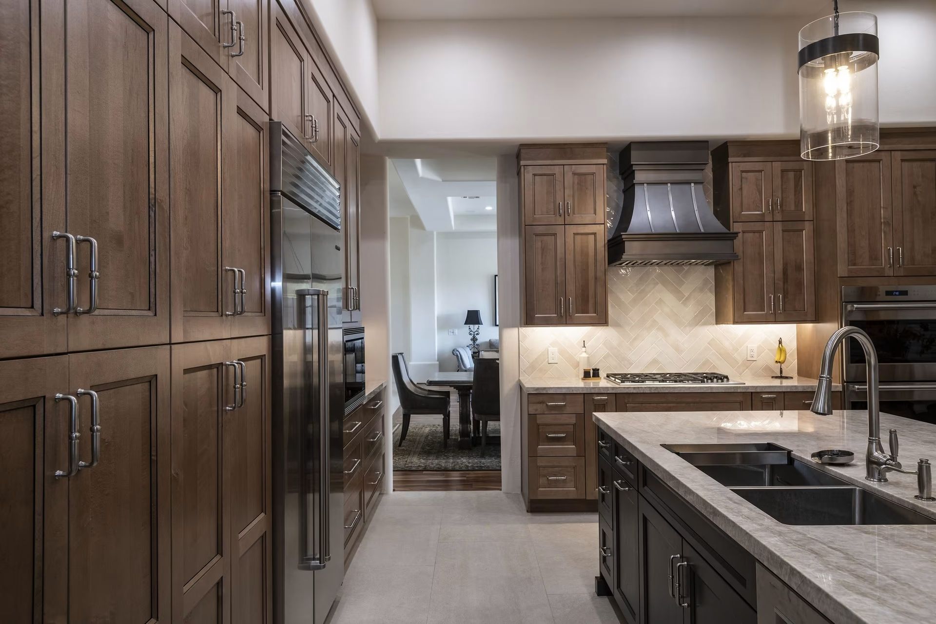 Modern kitchen with dark wood cabinets, island sink, stainless steel appliances, and pendant lighting