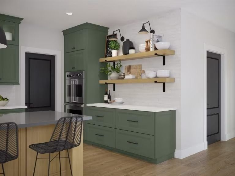 Modern kitchen with green cabinets, floating shelves, black stools, and light wood flooring