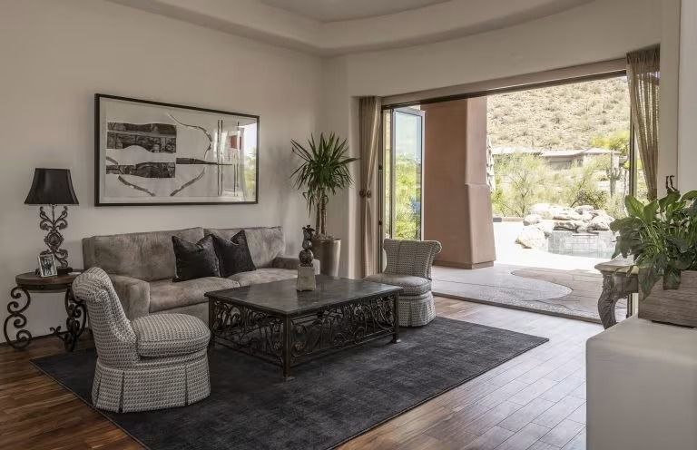 Modern living room with gray sofa, dark coffee table, and open sliding doors to a patio.
