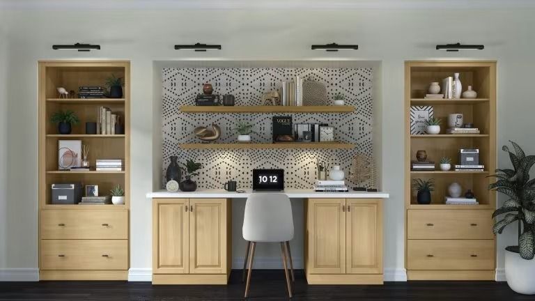 Home office with built-in shelves, desk, chair, and light wood cabinets against a patterned backsplash
