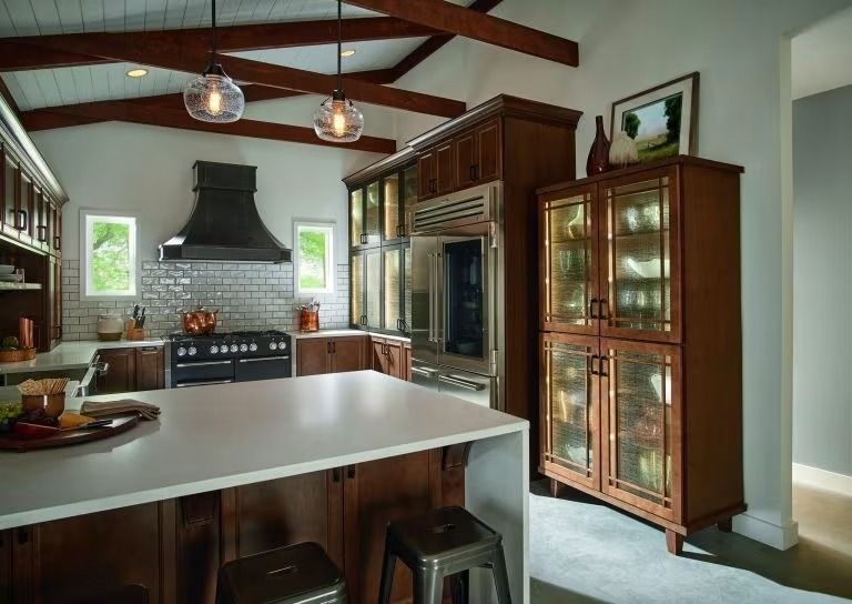 Modern kitchen with white island, dark wood cabinets, stainless stove, and glass display cabinet