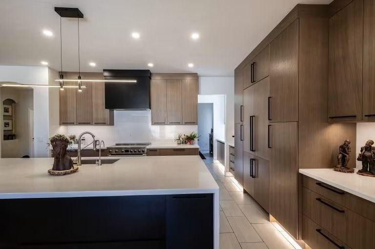Modern kitchen with wood cabinets, white countertops, island, and recessed ceiling lights